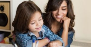 A mother and daughter pair where the mother is teaching the daughter to read.